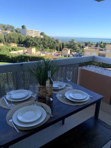 a table with plates and wine glasses on a balcony at Appartement vue mer tout confort in Villeneuve-Loubet +18 photos