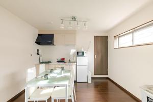 a white kitchen with a table and white appliances at en stay 005 in Osaka