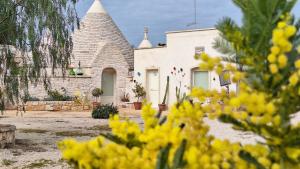 a white house with a turret and yellow flowers at Residenza Anima Mediterranea in Francavilla Fontana