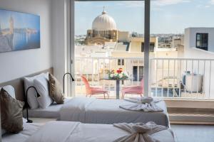 1 dormitorio con 2 camas y balcón con vistas. en Orbis Boutique Studios by Holi, en Qormi