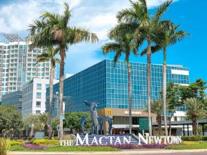 a large building with palm trees in front of it at Modern 1BR w Exclusive Pool Access in Lapu Lapu City