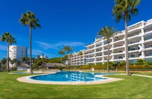 a large apartment building with a swimming pool and palm trees at Mi Capricho Calahonda in Mijas