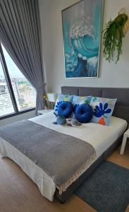 um quarto com uma cama com almofadas azuis e uma janela em Seabreeze 1BR Suite with Gorgeous Infinity Pool em Kuala Lumpur