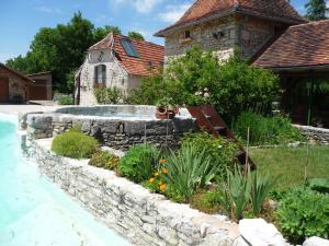 a garden with a stone retaining wall and a swimming pool at Tente Perchée Kenya MAS DE BOUZOU in Grèzes
