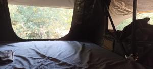 a bed in the back of a tent with a window at Tente Perchée Kenya MAS DE BOUZOU in Grèzes