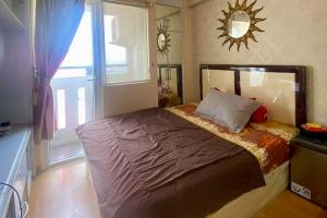 a bedroom with a bed with a window and a mirror at Green Pramuka by Uchi Property in Jakarta