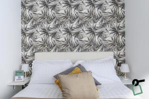 a bedroom with a white bed with a tropical wallpaper at HOTIDAY Room Collection - Napoli Centro Storico in Naples