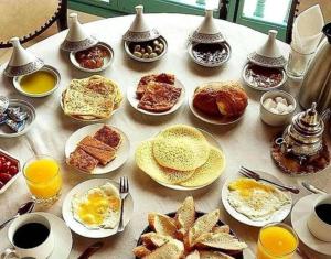 a table topped with plates of breakfast foods and drinks at Natural Farming in Sidi Bibi