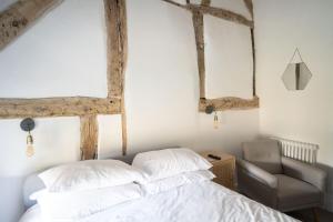 a bedroom with exposed beams and a bed and a chair at Seven Abbey Lane in Southam