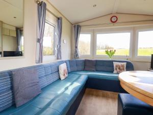 a blue couch in a living room with windows at Little Trevorrick Caravan in Wadebridge