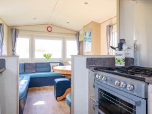 a kitchen with a stove and a living room at Little Trevorrick Caravan in Wadebridge