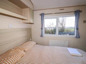 a bedroom with a large bed with a window at Little Trevorrick Caravan in Wadebridge