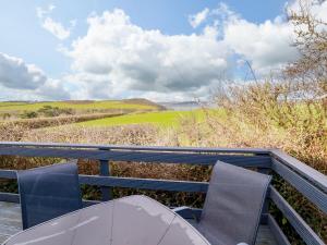 a table and chairs on a balcony with a view of the countryside at Little Trevorrick Caravan in Wadebridge
