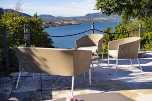 three chairs and a table with a view of the water at Villa Anna Lake View in Pilzone