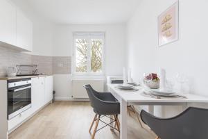 a white kitchen with a white table and chairs at Dubrovnik Appartment 2 in Krefeld