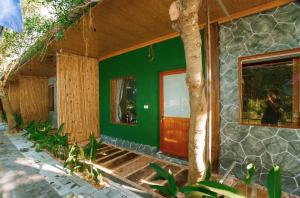 a green house with a red door and a tree at TRang an Mountain Ecolodge in Xuân Sơn