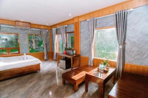 a bedroom with a bed and a table and windows at TRang an Mountain Ecolodge in Xuân Sơn
