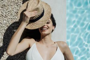 a woman wearing a straw hat next to a pool at Domìa Boutique Hotel e Cucina in Mondello