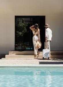 a man and a woman with a suitcase next to a pool at Domìa Boutique Hotel e Cucina in Mondello