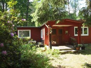 a small red house with a porch in a yard at Traum Waldhaus in Seppensen