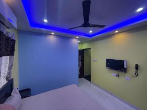 a bedroom with a ceiling fan and a tv on the wall at Park kasba Inn in Kolkata