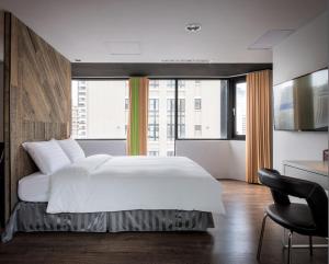 a bedroom with a white bed and a large window at Calligraphy Greenway Hotel in Taichung
