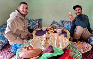 a couple of men sitting around a table with food at Dar Ayoub in Inlghdene