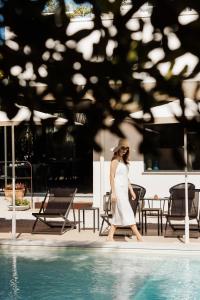 a woman in a white dress walking by a pool at Domìa Boutique Hotel e Cucina in Mondello
