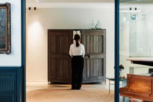 a woman standing in front of a wooden door at Domìa Boutique Hotel e Cucina in Mondello