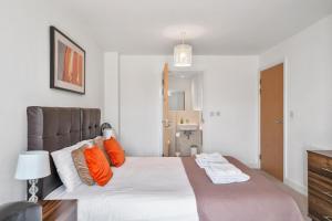 a bedroom with a large bed with orange pillows at Kennet House 2 Bedroom, 2 Bathroom Apartment in Reading