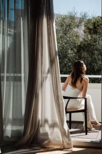 a woman sitting in a chair looking out of a window at Domìa Boutique Hotel e Cucina in Mondello