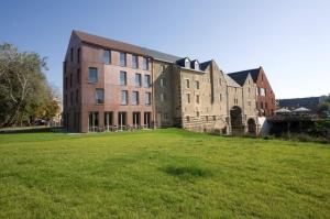 a large brick building on a field of grass at 'S Hertogenmolens Hotel in Aarschot