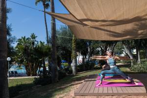 two women doing yoga on a yoga mat in a park at Sagitario Princesa Playa in Son Xoriguer