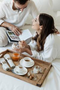a man and a woman in bed with a tray of food at Domìa Boutique Hotel e Cucina in Mondello
