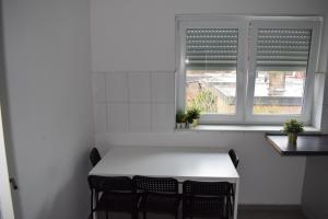 a white kitchen with a table and two windows at LK Apartment 02 in Gronau +1 photo