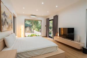 a bedroom with a large bed and a flat screen tv at Thiên Trường An Garden in Ninh Binh