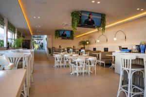a restaurant with white tables and chairs and televisions at Kastro Beach Apartments in Malia