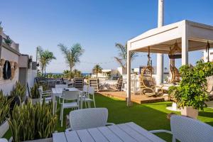 a patio with white tables and chairs and a playground at Kastro Beach Apartments in Malia