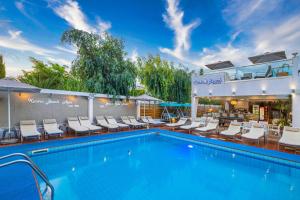 a pool at a hotel with lounge chairs at Kastro Beach Apartments in Malia