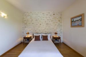 a bedroom with a large white bed with two lamps at Villa Manolia in Prinés +9 photos