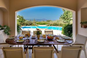 a dining room with a table and chairs and a pool at Villa Manolia in Prinés