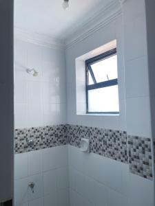 a white bathroom with a shower and a window at Imastay in Mombasa