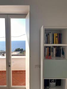 a book shelf with books and a view of the ocean at Apartment in Villa Argentina in Capri
