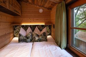 Una cama en una habitación de madera con ventana. en Ferienhof und Baumhaushotel, en Betzigau