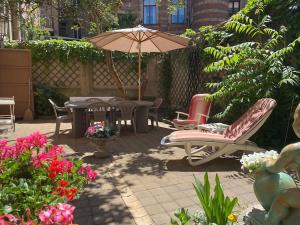 eine Terrasse mit Tisch und Stühlen und einem Sonnenschirm in der Unterkunft Maison Koch · Maison bourgeoise - 240 m2 in Straßburg