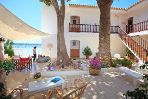 a patio with tables and chairs and palm trees at Hostal la Savina in La Savina