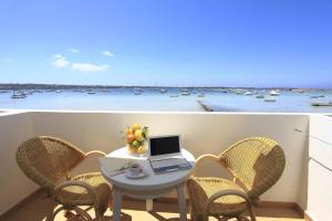 a table with a laptop on a balcony with a view of the ocean at Hostal la Savina in La Savina