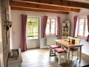 a dining room with a table and two windows at kleine meerZeit, süßes Knusperhäuschen mit Kaminofen in Fehmarn