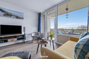 a living room with a tv and a large window at Ferienwohnung Sydvind 8408 Marina Wendtorf in Wendtorf