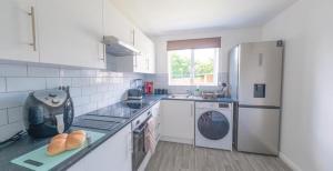 a kitchen with a refrigerator and a sink and a dishwasher at Sleeps 5 - Private Garden- Free Parking in Corby